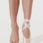 Ballet shoes with straps worn by a dancer on a white background