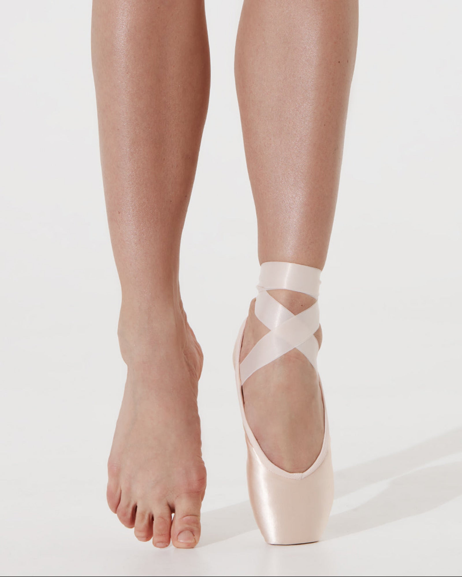 Ballet shoes with straps worn by a dancer on a white background