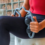 Person using a gray leg massager on a white cushioned chair with a blurred background