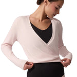 Woman wearing a light pink wrap top over a black leotard on a white background