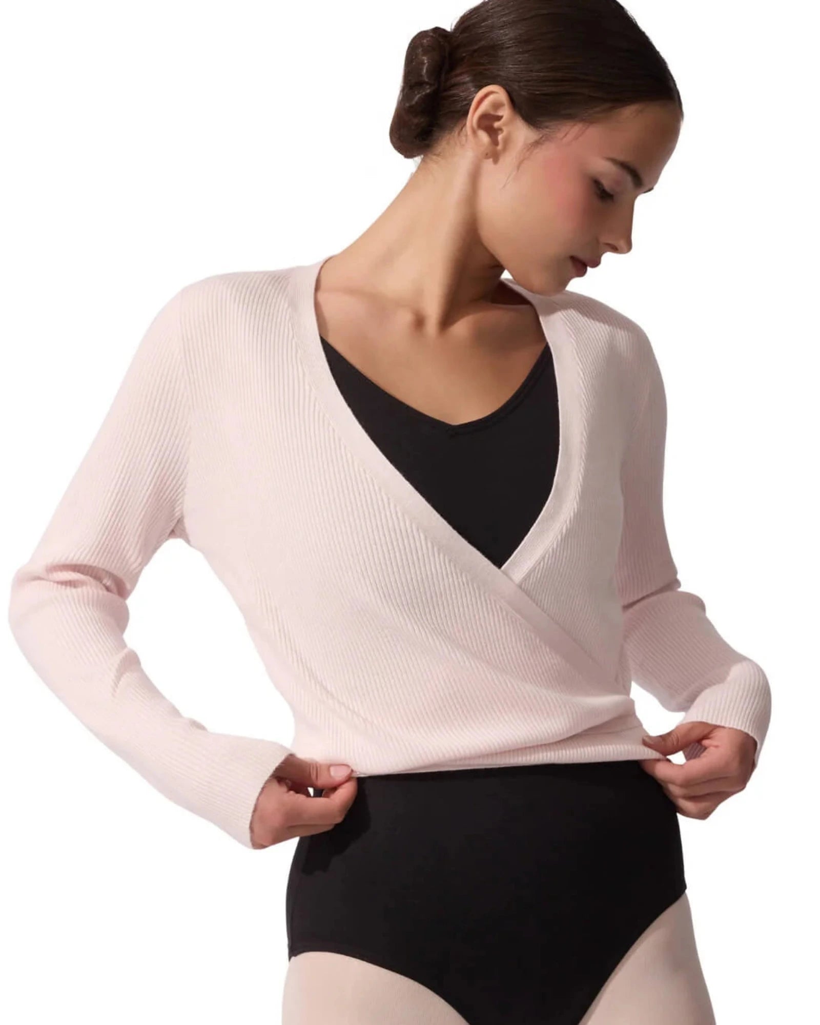 Woman wearing a light pink wrap top over a black leotard on a white background