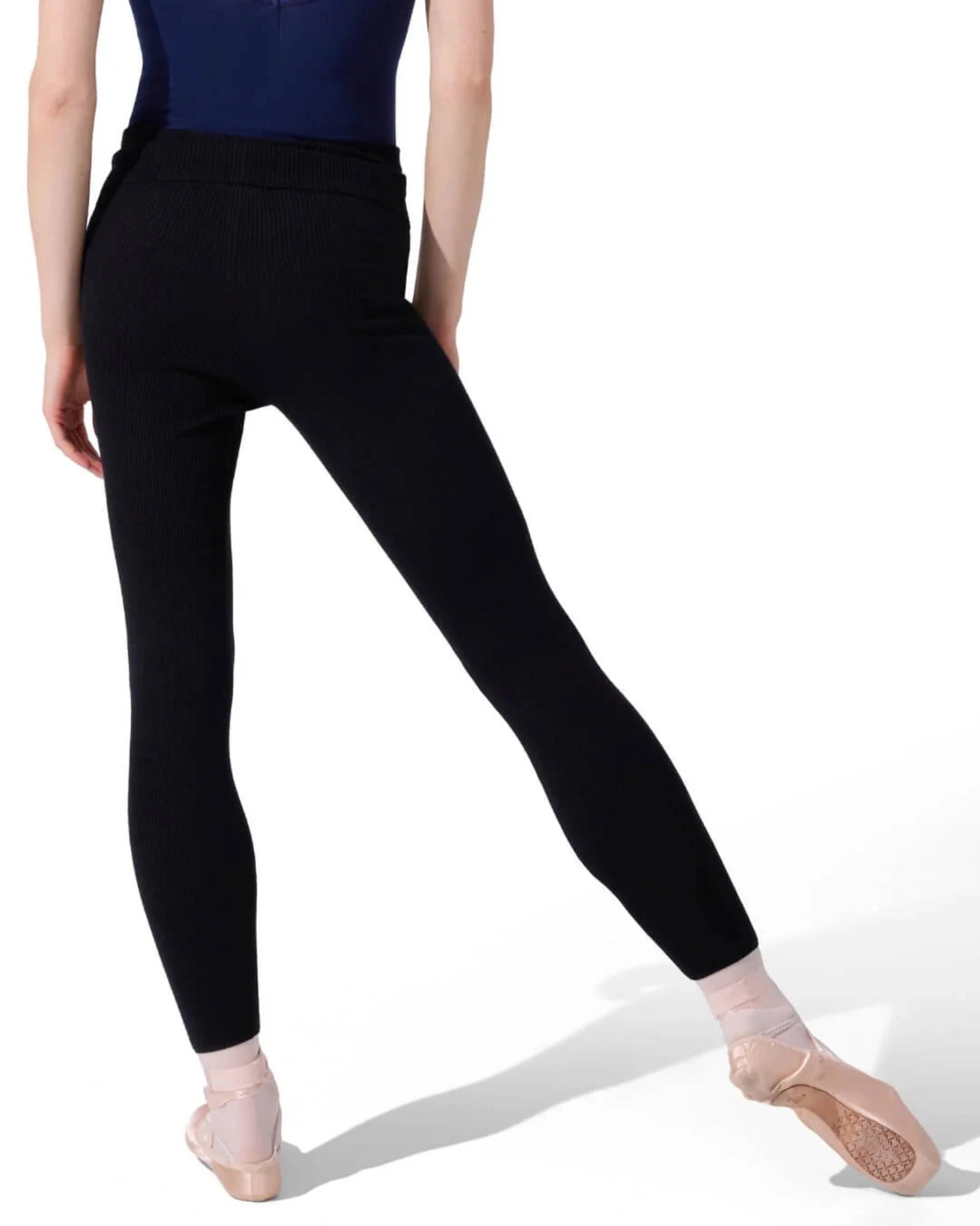 Person wearing a navy leotard and black sweater tights on a white background