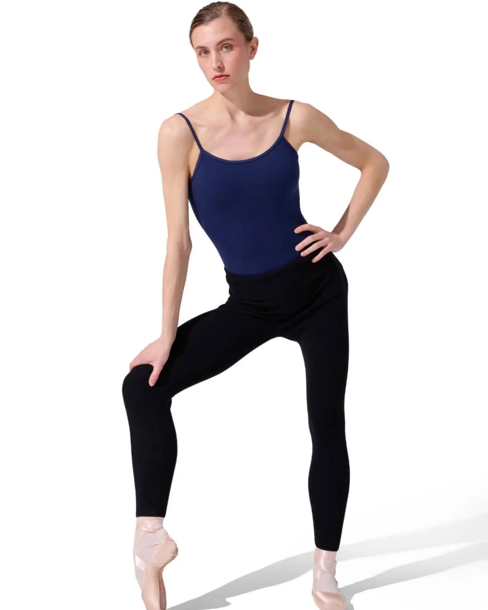Dancer in a navy leotard and black sweater tights posing on a white background