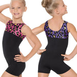 Two young girls wearing black leotards with patterned tops on a white background