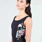 Woman wearing a black leotard with floral design on a light gray background