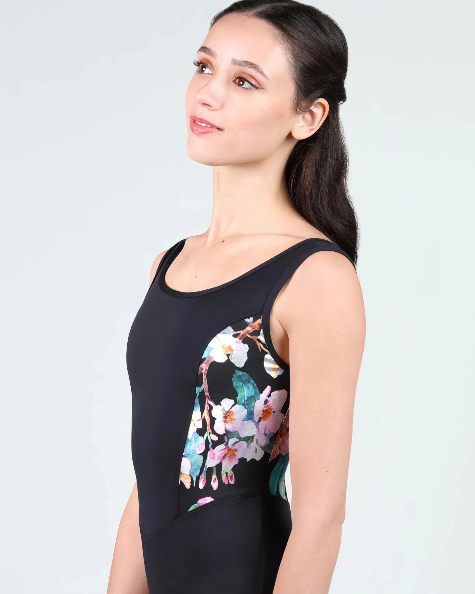 Woman wearing a black leotard with floral design on a light gray background