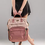 Person holding a pink backpack against a gray background