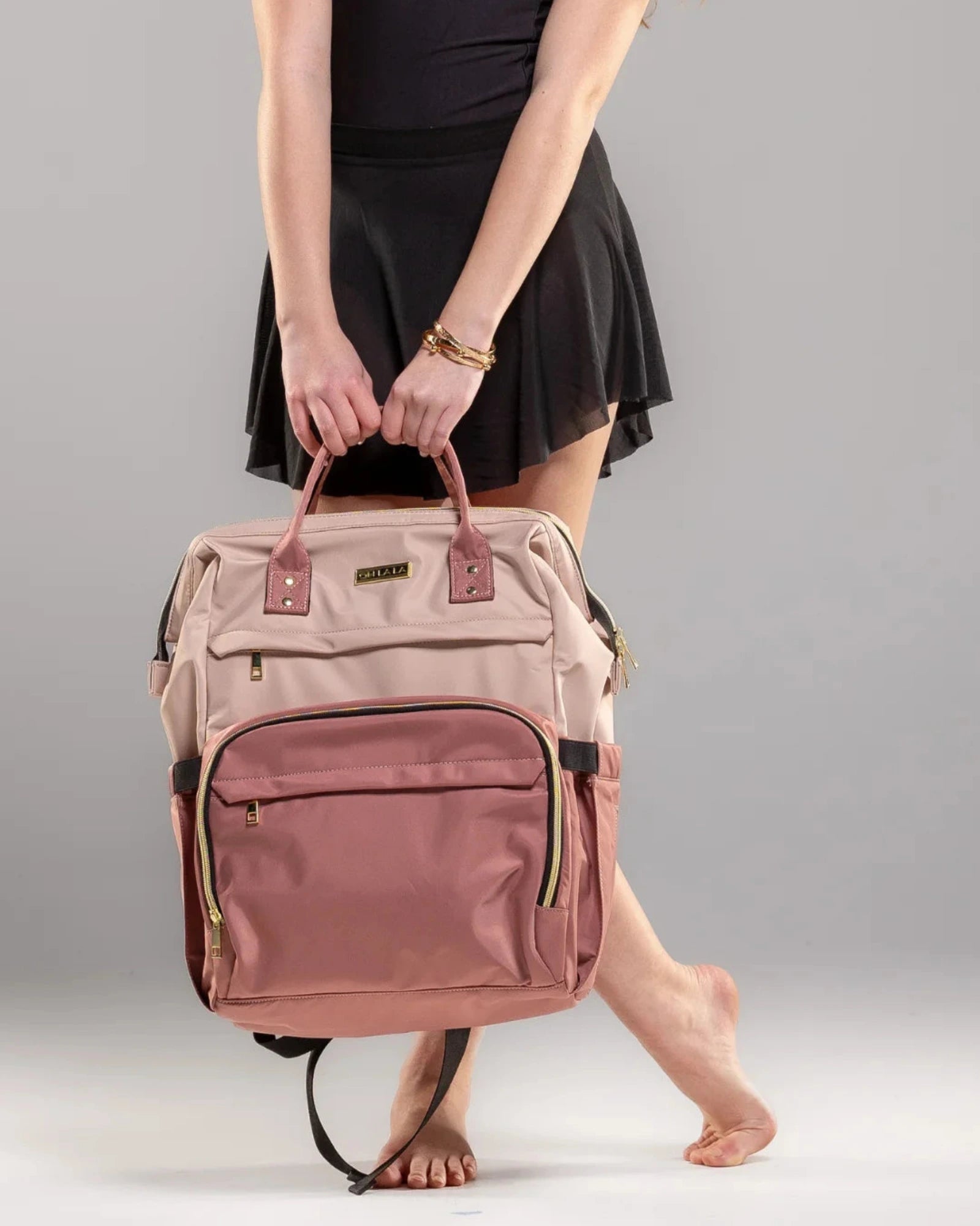 Person holding a pink backpack against a gray background