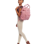 Woman wearing a pink corduroy backpack on a white background