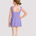 Young girl in a purple leotard standing against a plain background