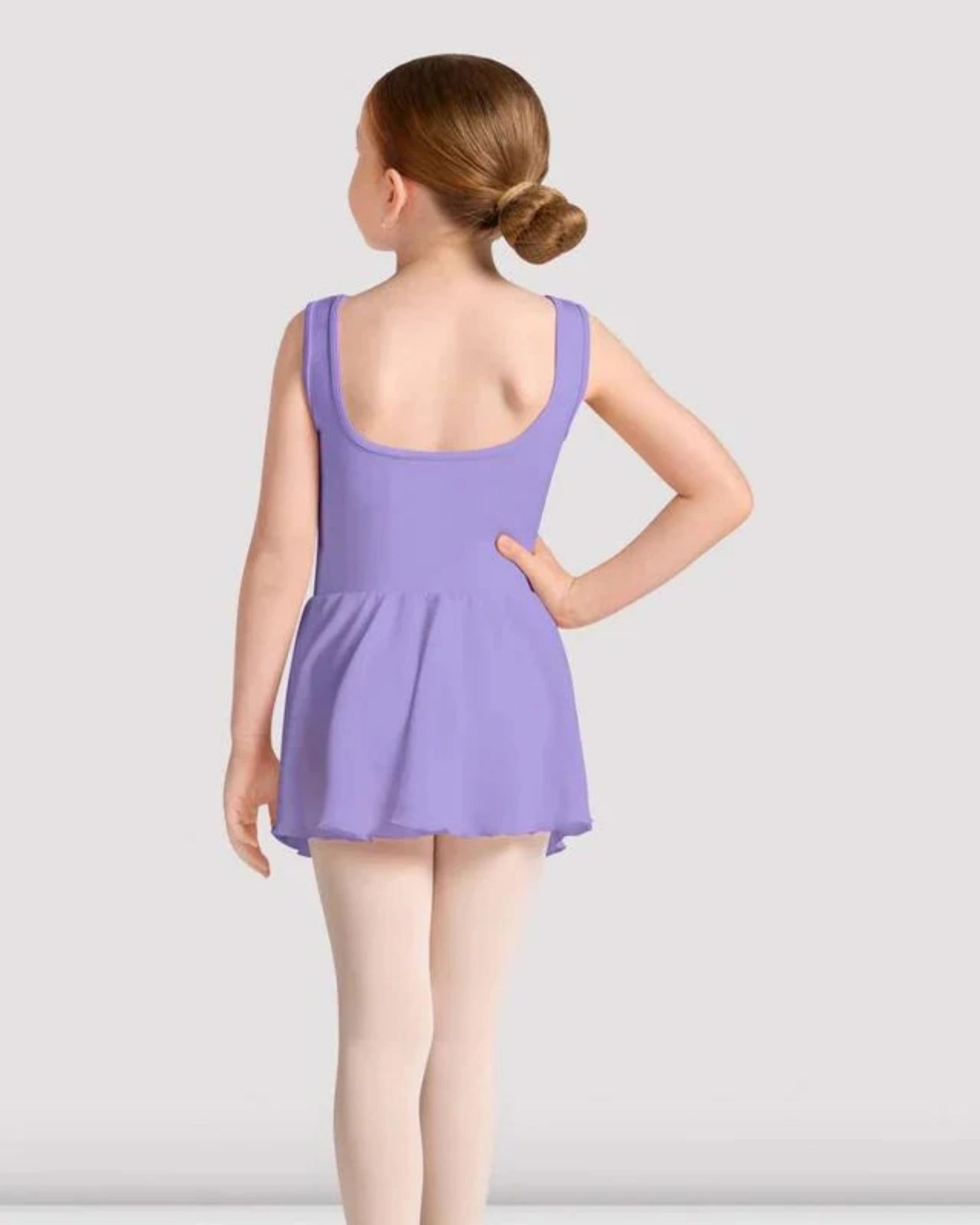 Young girl in a purple leotard standing against a plain background