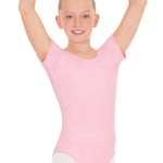Young girl in a pink leotard with arms raised on a white background