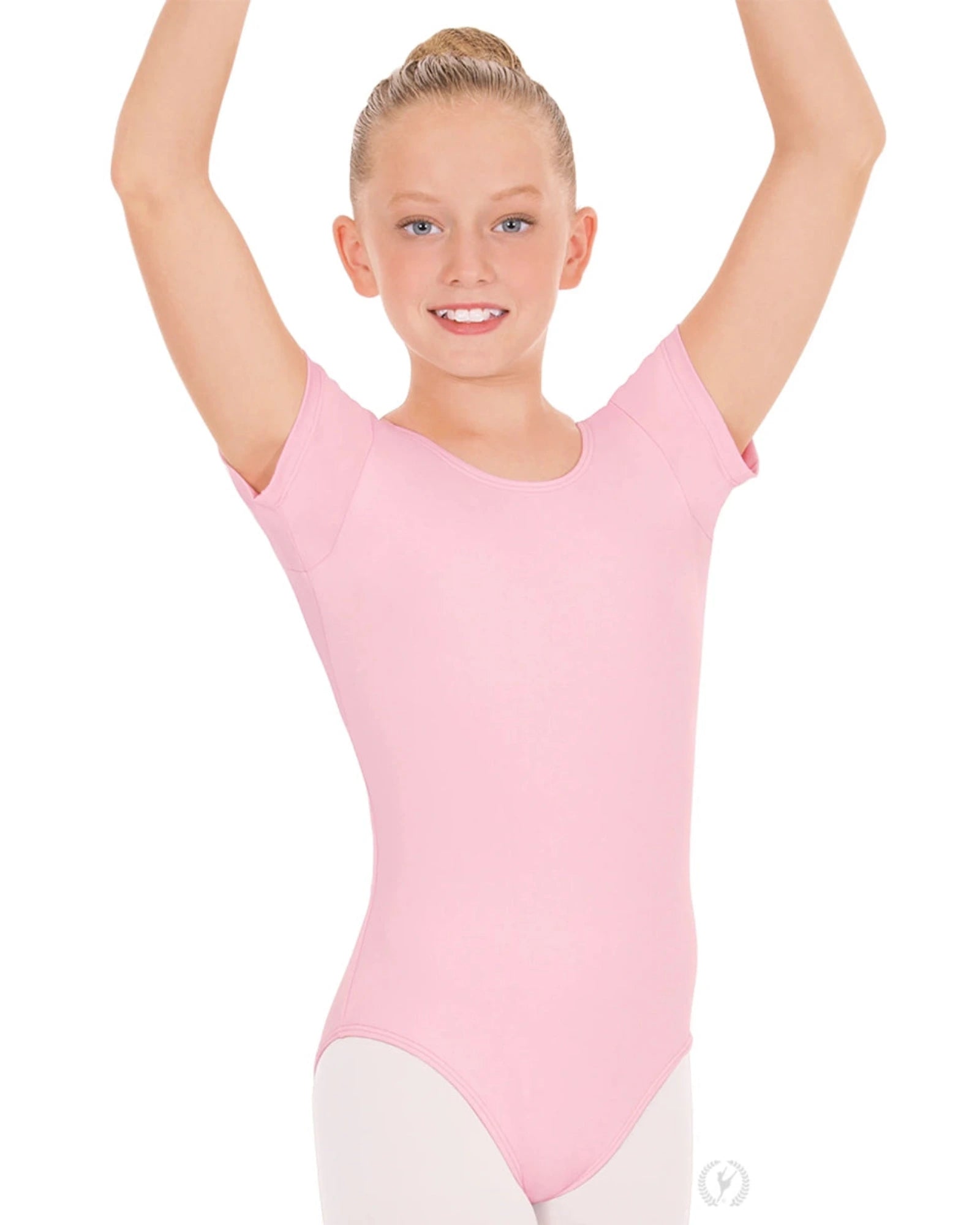 Young girl in a pink leotard with arms raised on a white background