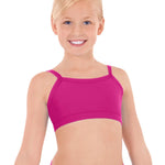 Young girl wearing a pink sports bra and shorts on a white background