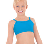 Young girl wearing a blue bra top and blue shorts on a white background