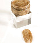 Gold glittery cream in a small jar with a sample on a white background