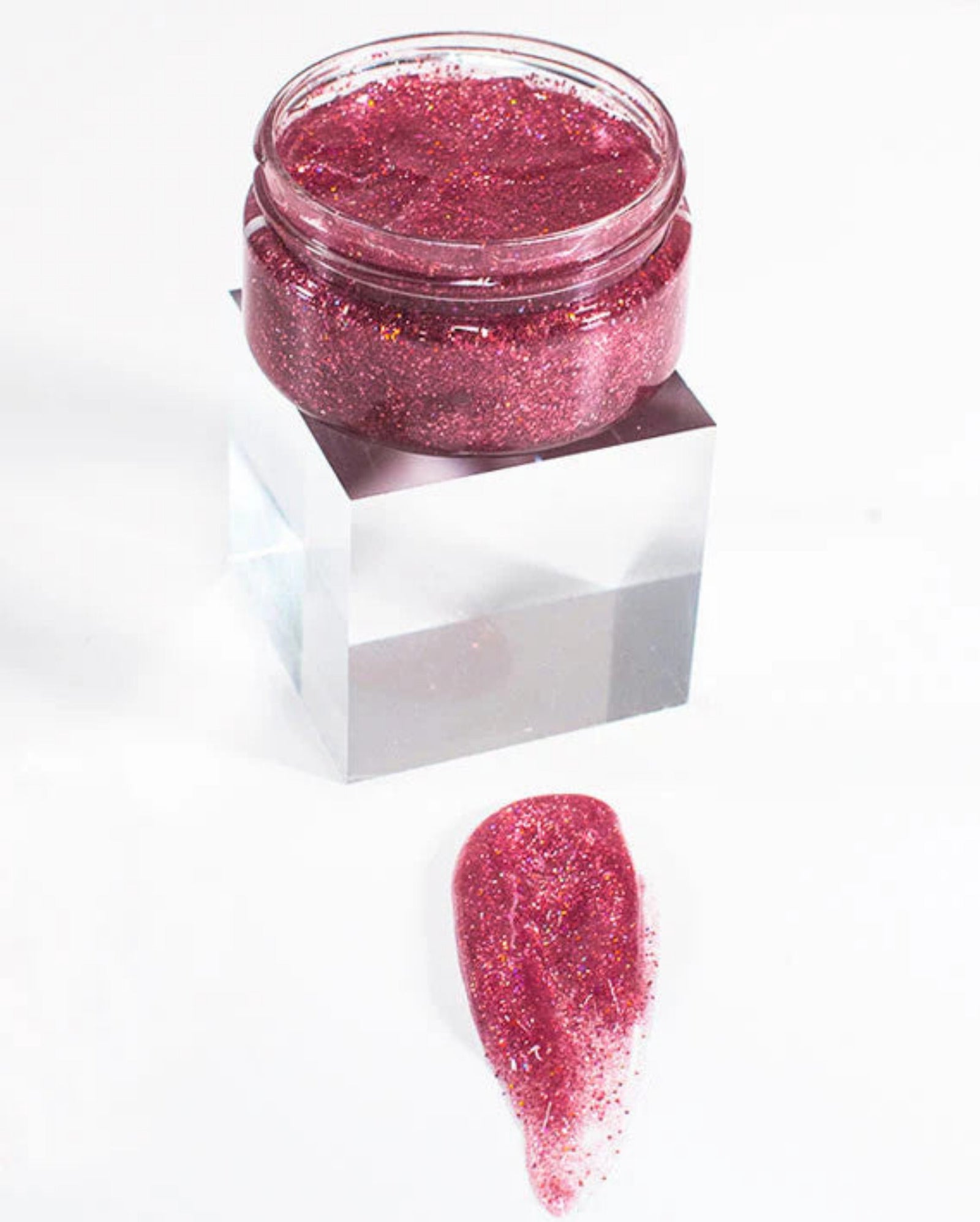Pink glittery substance in a small jar on a white background