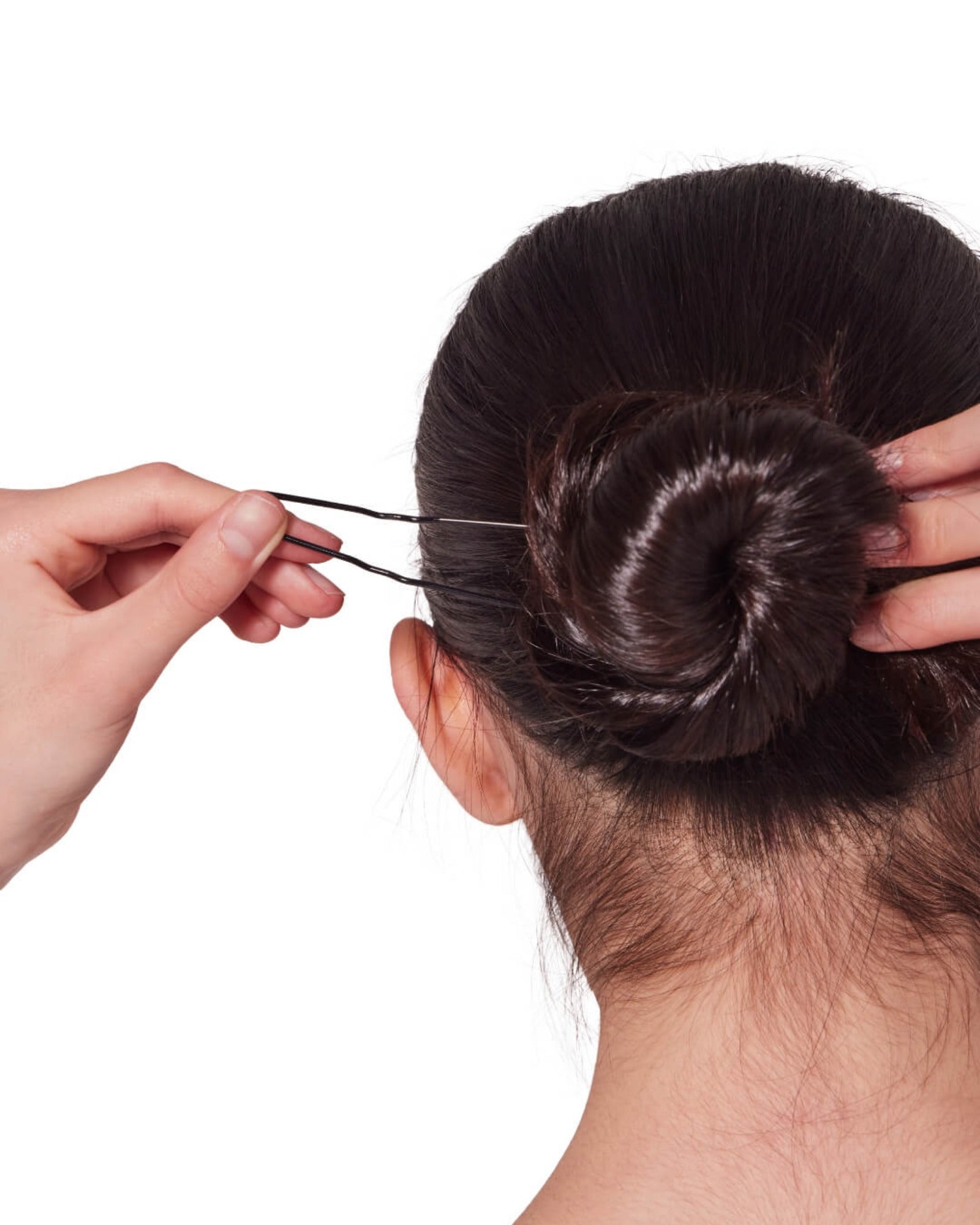 Person styling a bun with hair pins on a white background