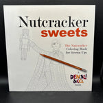 The Nutcracker Sweets coloring book for grown-ups by Denali & Co., featuring a white cover with black and red text and line art of a nutcracker and a child, with a wooden pencil resting across the front, set against a dark background.