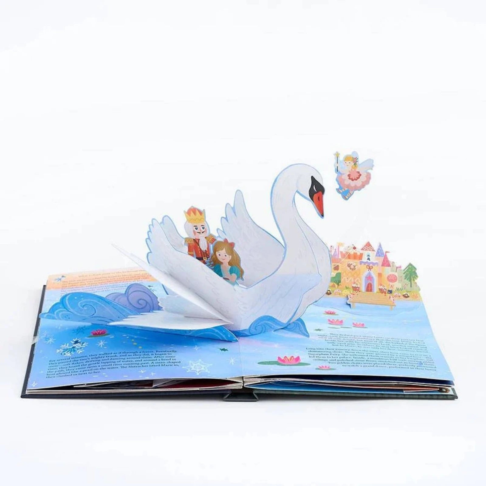 An open 3D pop-up children's book featuring a white swan carrying a Nutcracker and Clara, with a castle, water, and a small angel figure on the illustrated pages against a white background.