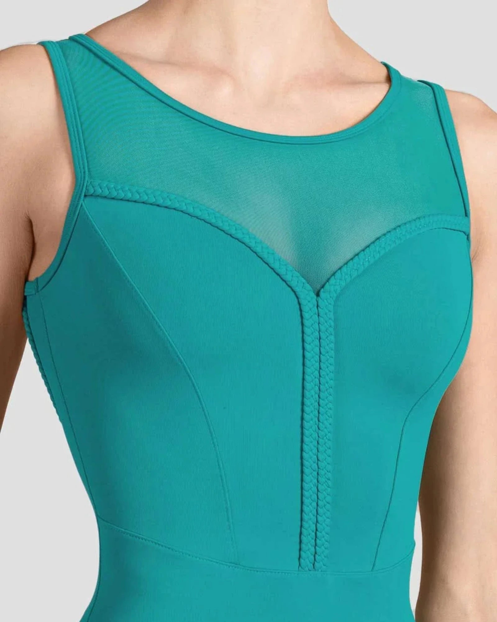 A close-up of a teal green sleeveless bodysuit or leotard with a sheer mesh V-neckline and structured corset-style front panels, shown on a model against a light gray background.