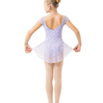 A young girl dancer viewed from behind, wearing a light lavender and white patterned tutu leotard, standing on a solid white background.