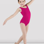 A young girl dancer posing in a bright magenta sleeveless leotard and nude tights against a light gray studio background.