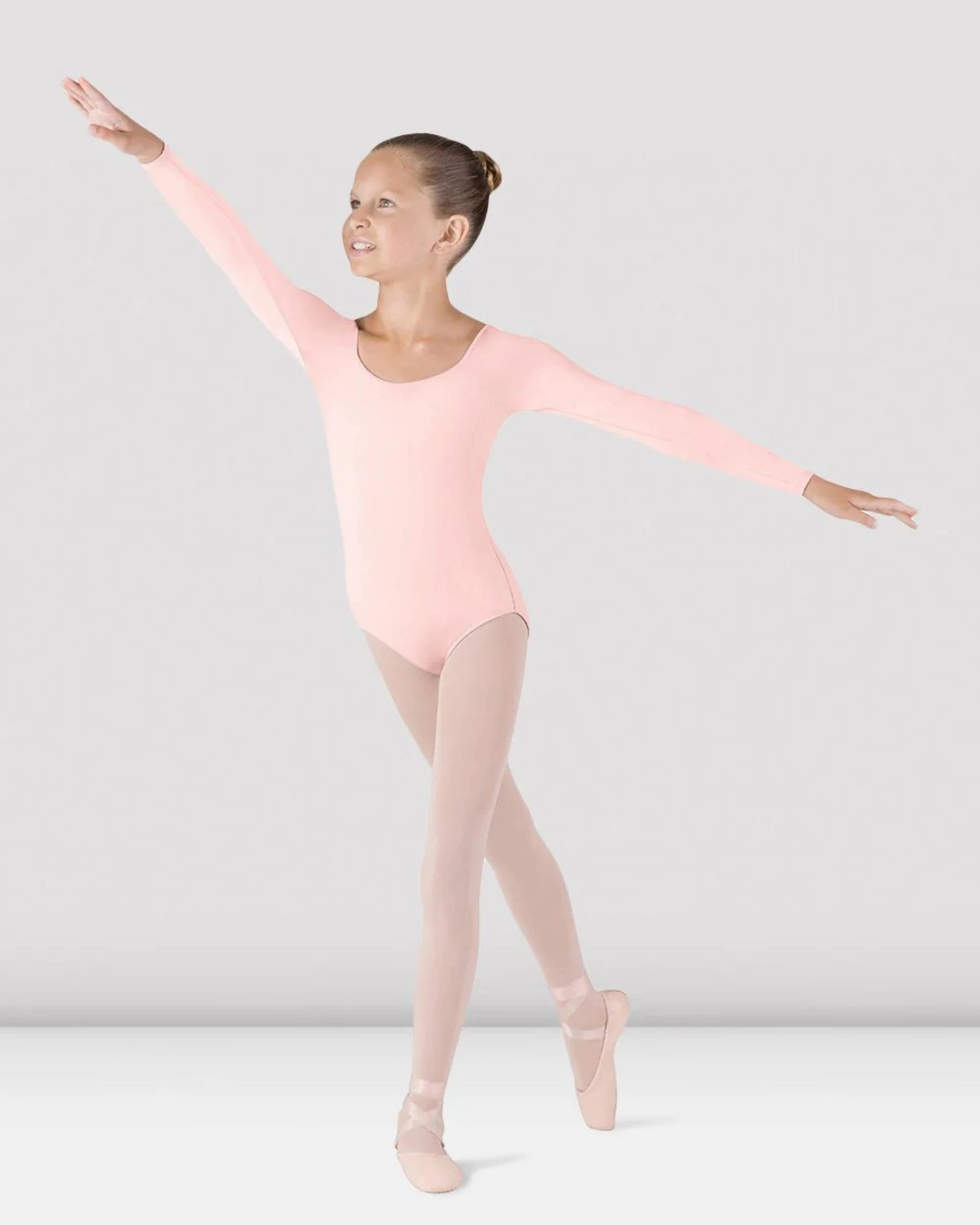 Ballerina in a pink leotard and tights posing against a plain background