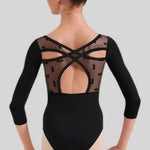 A woman modeling a black three-quarter sleeve dance leotard from the back, showing a sheer mesh back panel with decorative black lace and crisscross straps. 