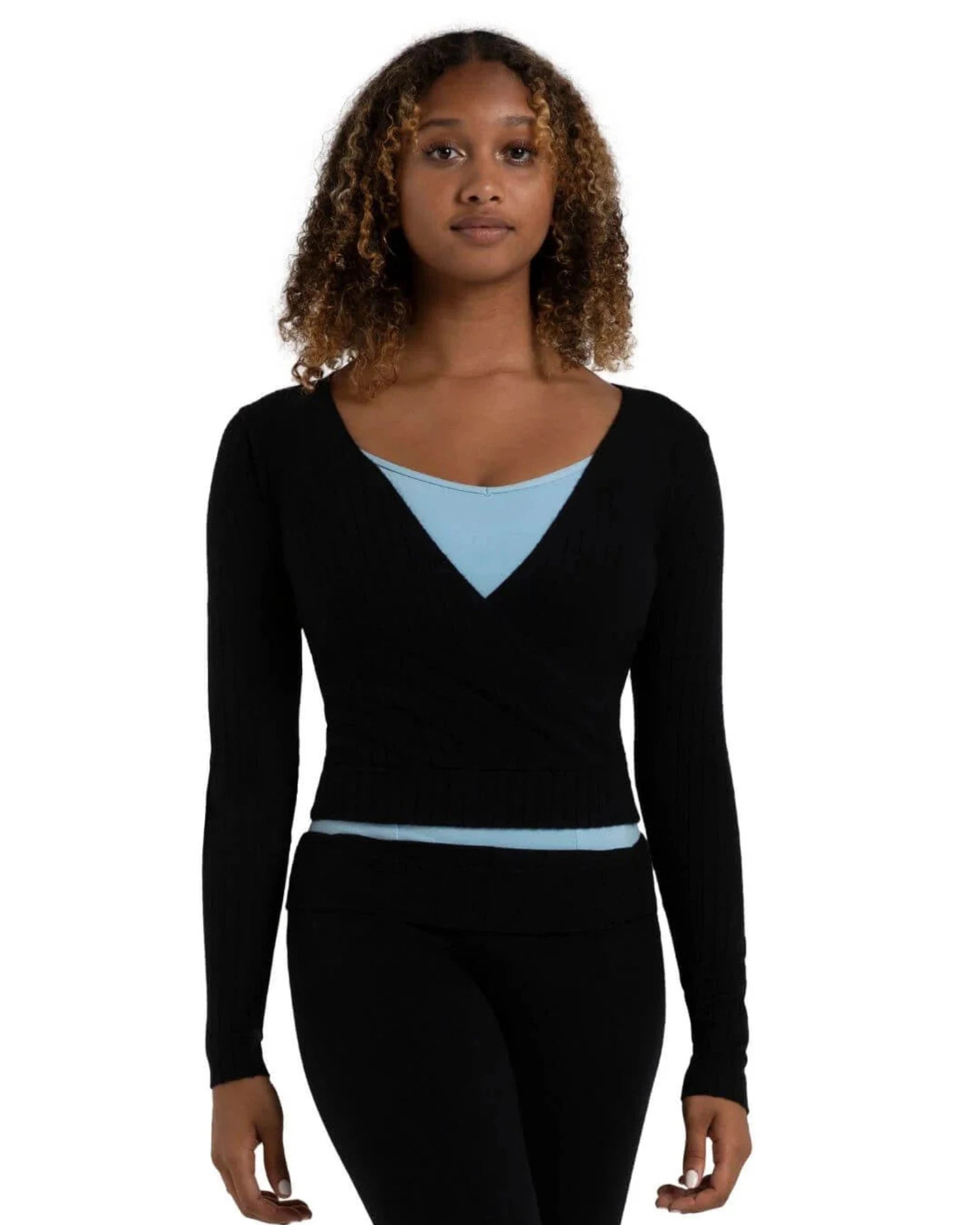 A woman modeling a black long-sleeve wrap-style knit top with a light blue V-neck undershirt and black leggings, shown against a plain white background.