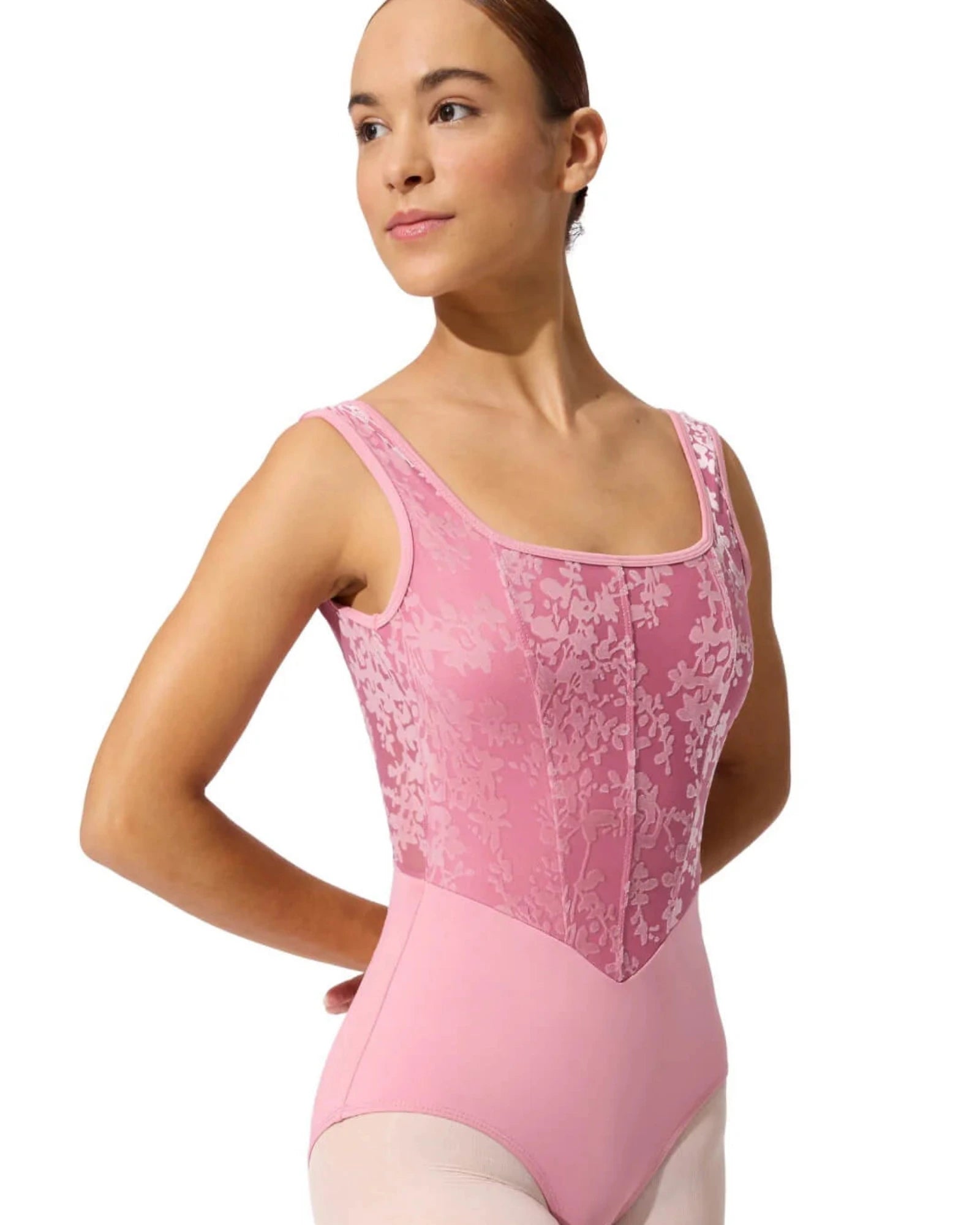 Ballerina wearing a pink leotard with lace details on a white background