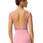 Woman wearing a pink leotard with lace detailing on a white background