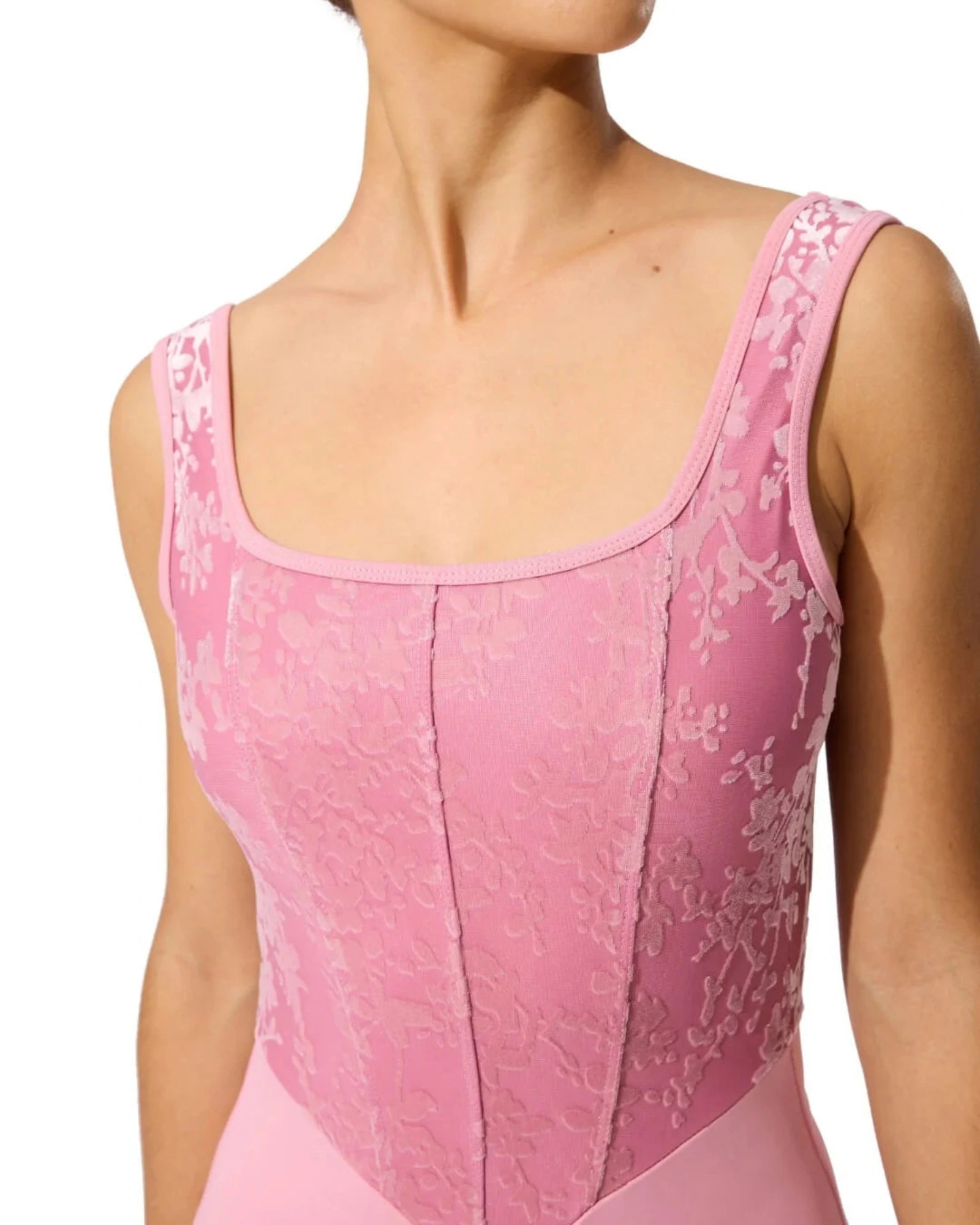 Close-up of a pink leotard with floral lace details on a white background