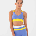 Woman wearing a blue and yellow bra top and shorts set on a white background