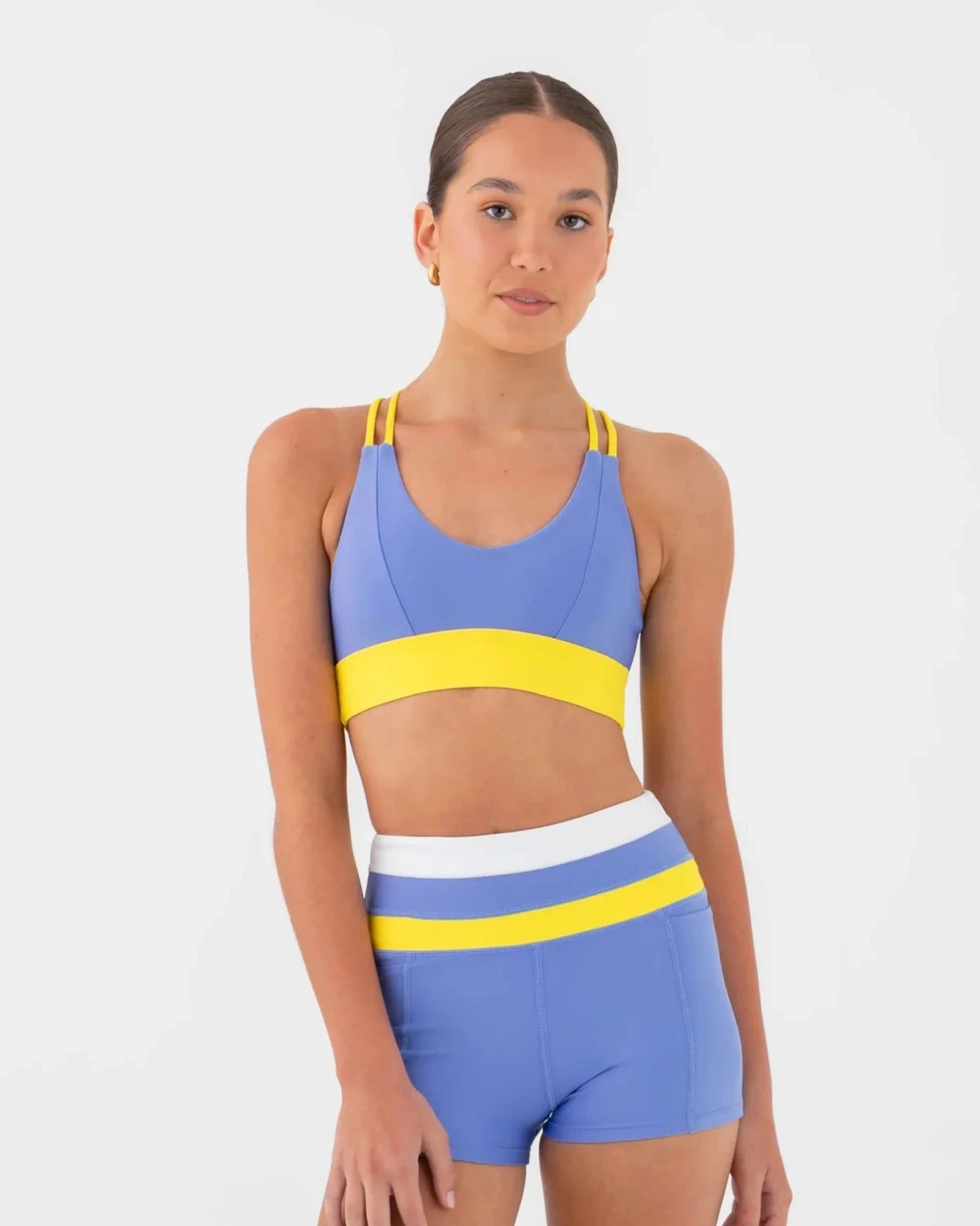 Woman wearing a blue and yellow bra top and shorts set on a white background