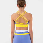A woman shown from the back wearing a matching dance set consisting of a bra top and shorts. The set features a light blue base color with bright yellow stripes and a white waistband.