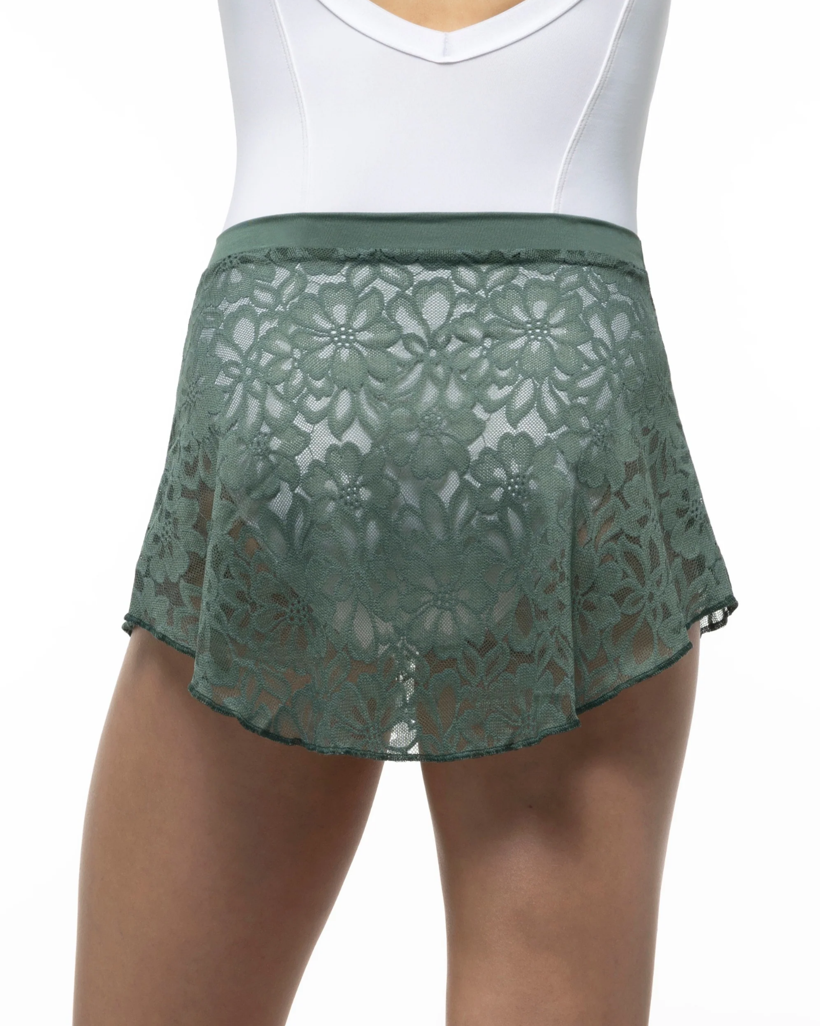 A close-up of a model wearing a sage green lace dance skirt with a matching elastic waistband, paired with a white bodysuit against a plain white background.