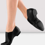 Black slip-on shoes worn by a person on a light gray background