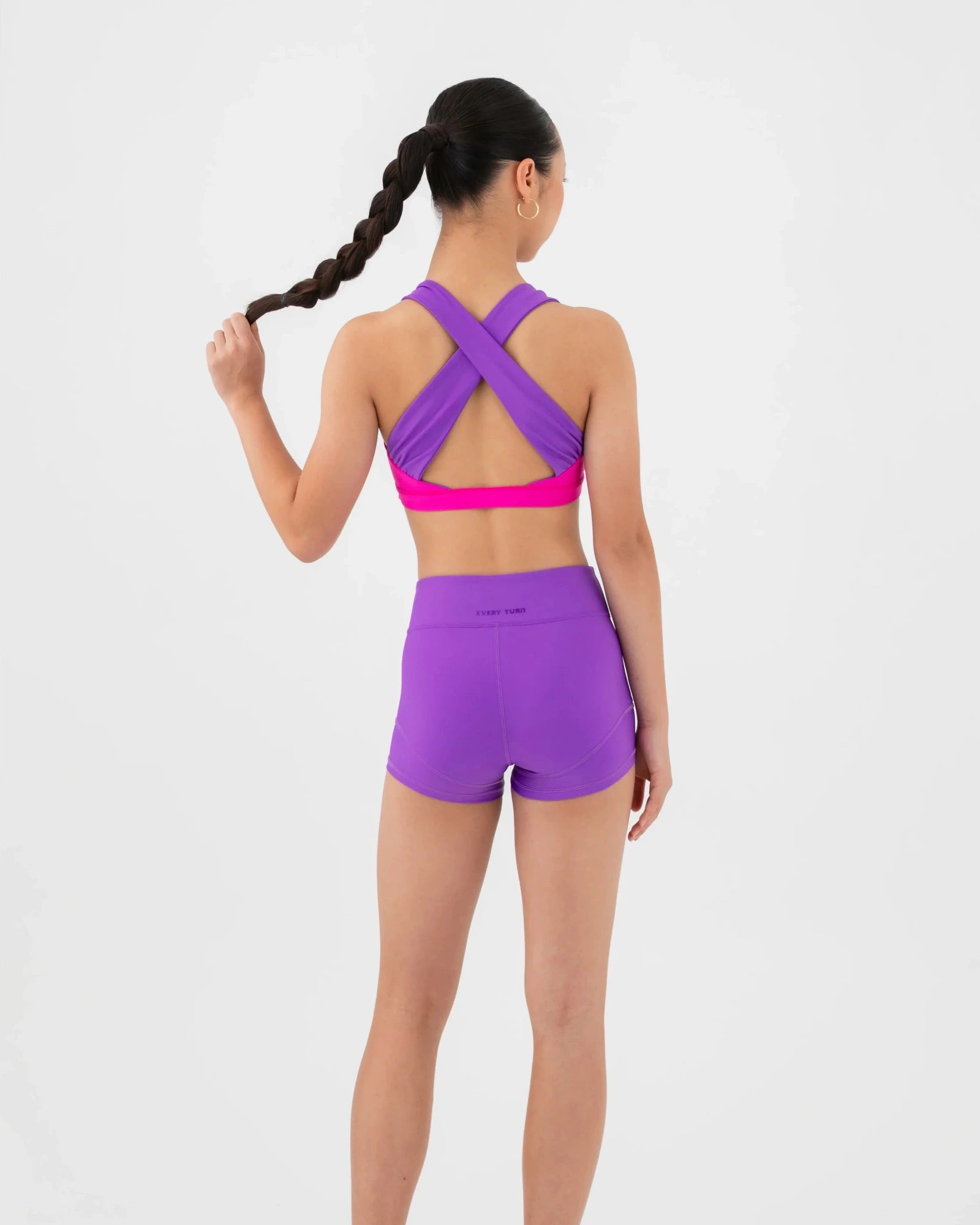 Person wearing a purple bra top and shorts set on a white background