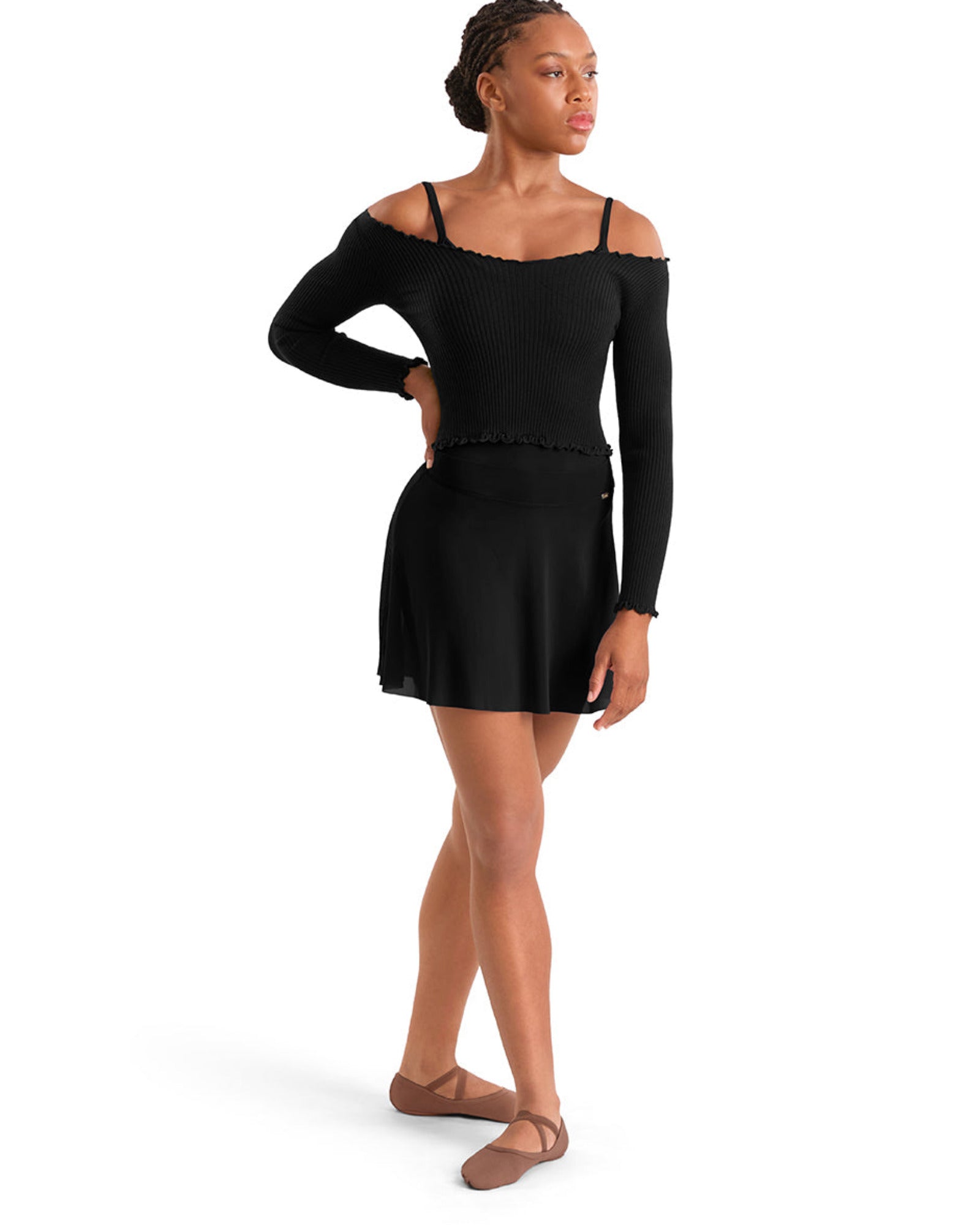 A woman modeling a black long-sleeve off-the-shoulder dance leotard top paired with a black skirt, shown from the side against a plain white background.