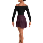 A woman modeling a black long-sleeve off-the-shoulder dance leotard and a dark plum pleated mini skirt, shown from the back against a solid white background.