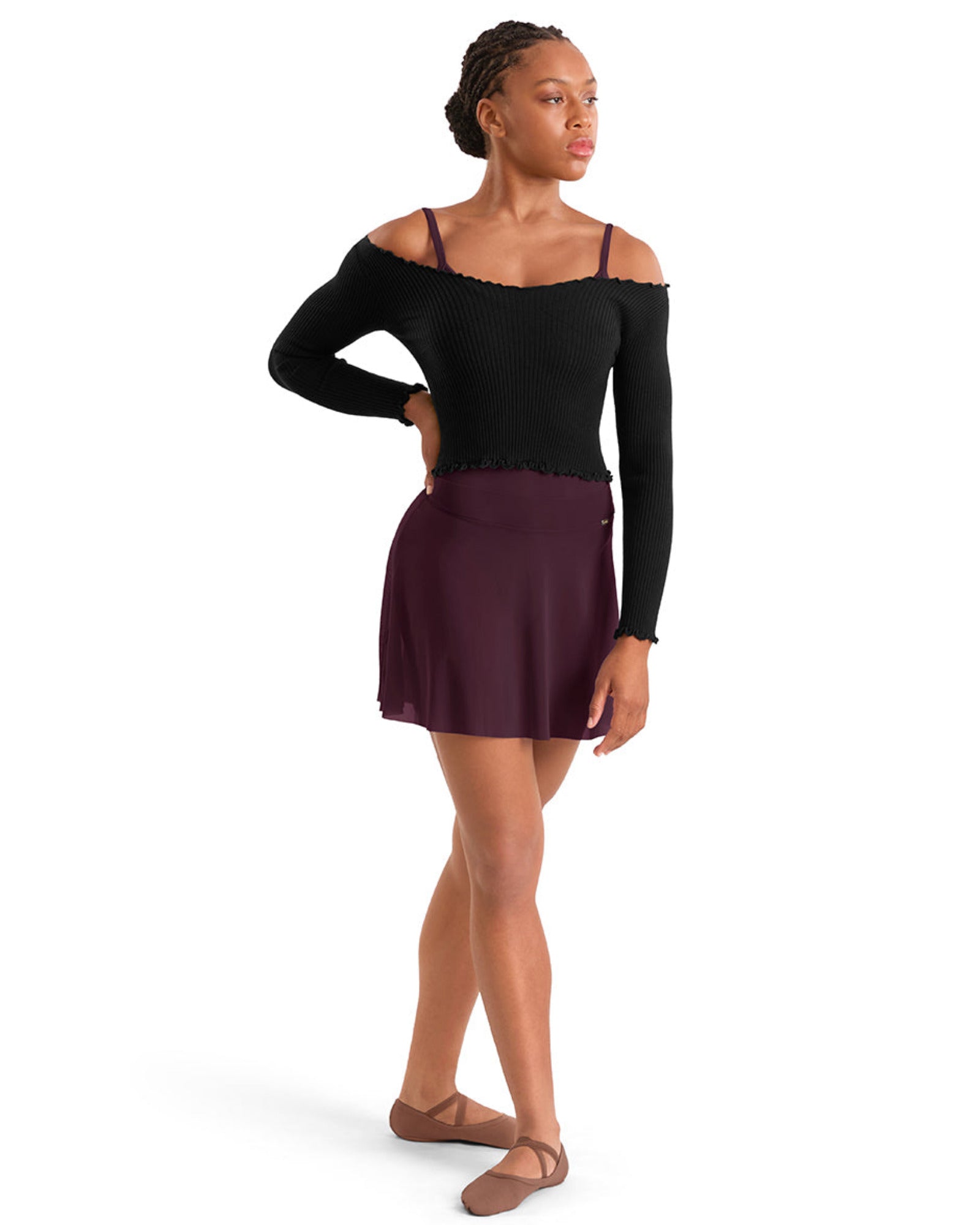 A woman modeling a black long-sleeve off-the-shoulder dance leotard top paired with a dark plum skirt, shown from the side against a plain white background.