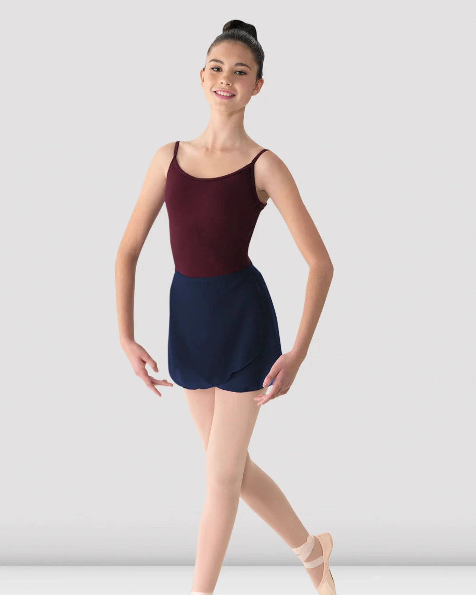 Ballerina in a maroon leotard with a navy skirt posing against a plain background