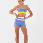 Woman wearing a blue and yellow bra top and shorts set on a white background