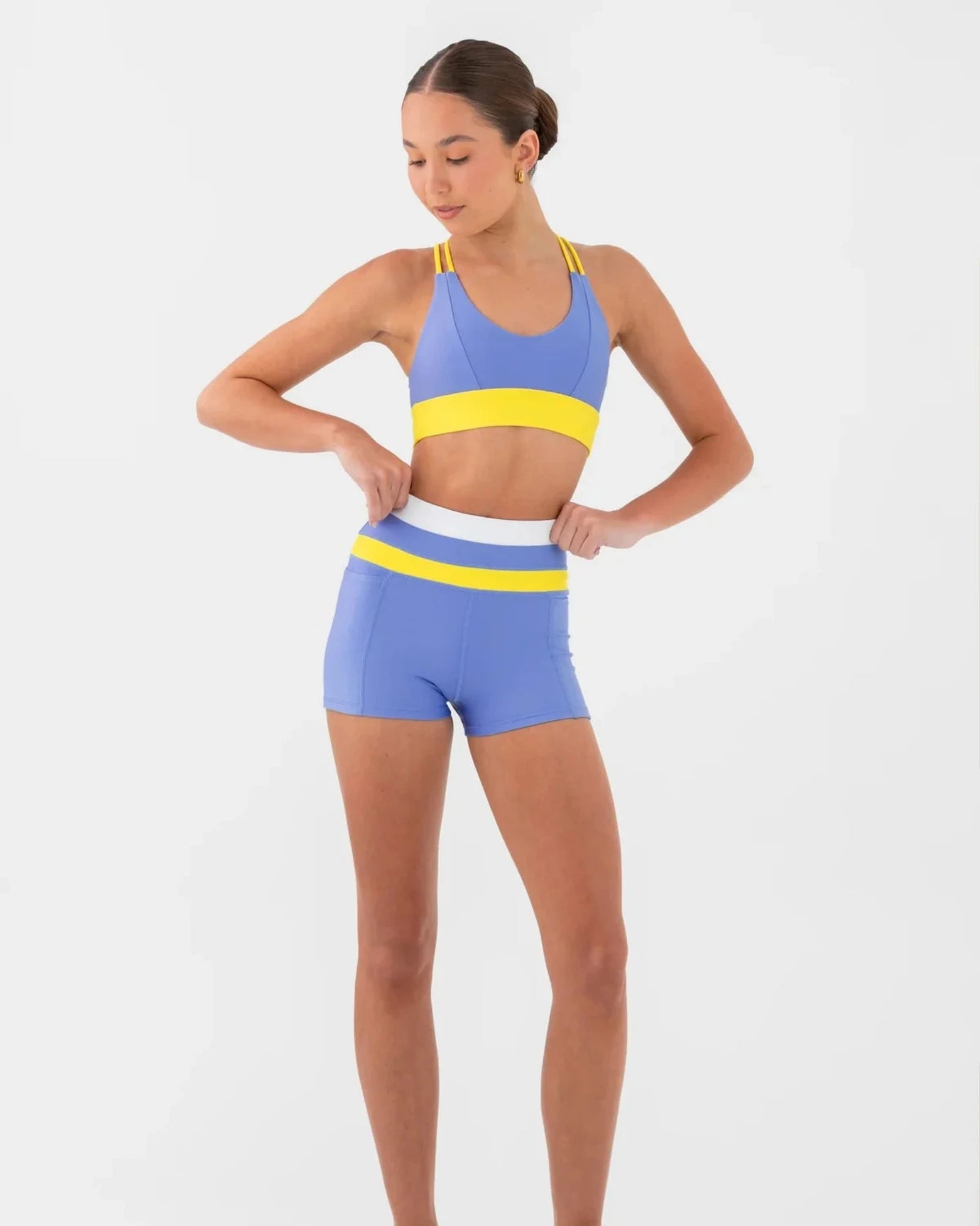 Woman wearing a blue and yellow bra top and shorts set on a white background