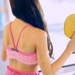 Woman in pink dance outfit holding a yellow paddle outdoors