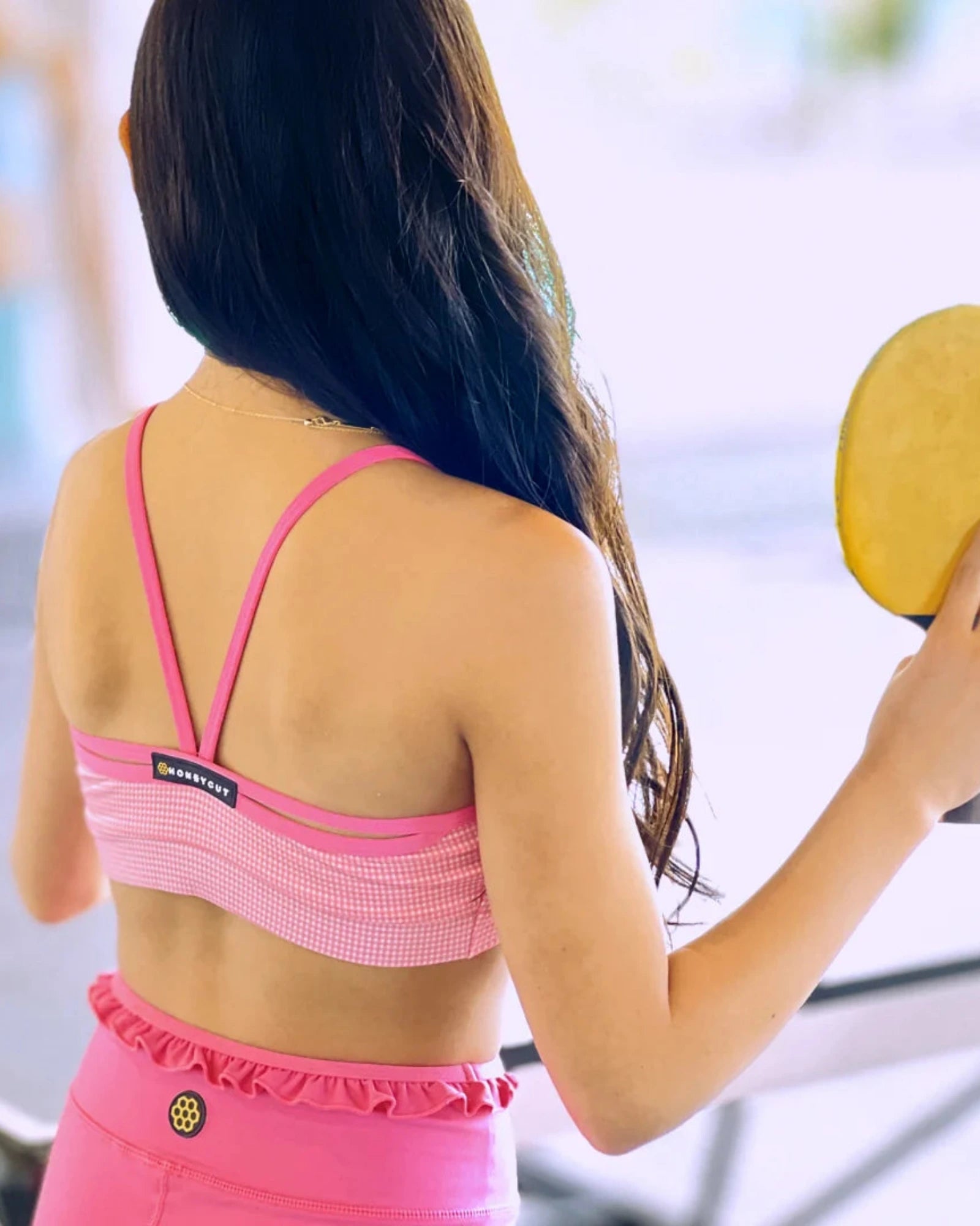 Woman in pink dance outfit holding a yellow paddle outdoors