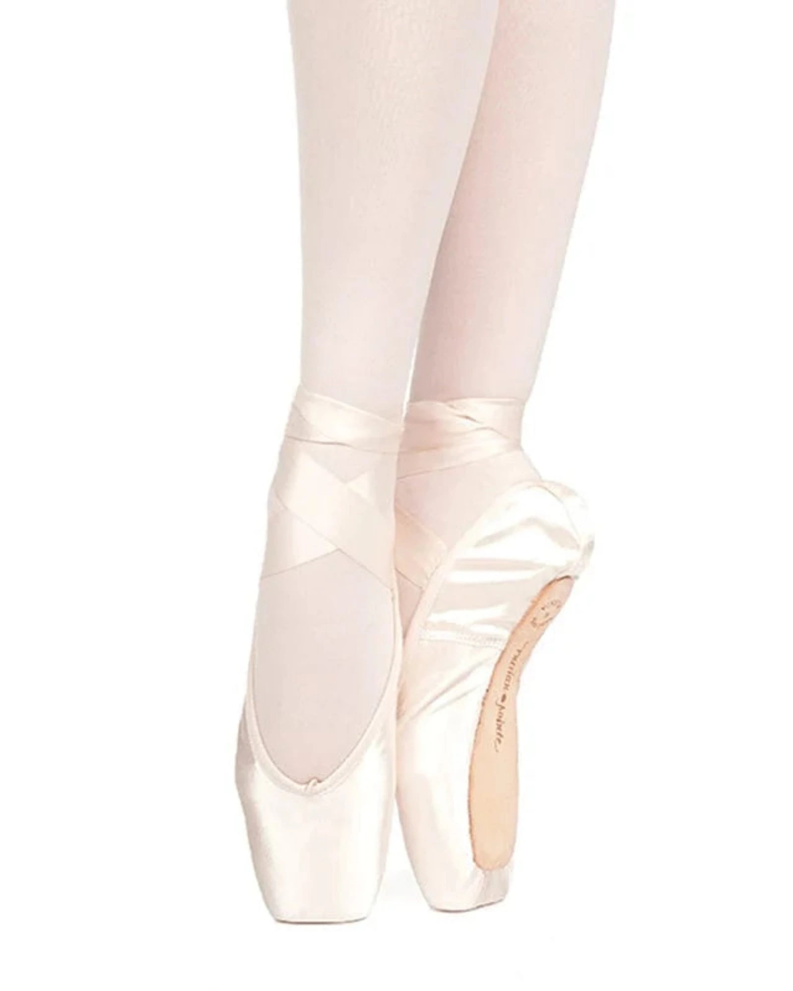 A pair of satin pointe shoes worn on a dancer's feet, shown in a side profile against a solid white background. The shoes are light pink with white satin ribbons and white tights.