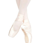 A pair of satin pointe shoes worn on a dancer's feet, paired with light pink tights against a solid white background.