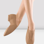 Nude-colored jazz shoes worn by a person on a light gray background